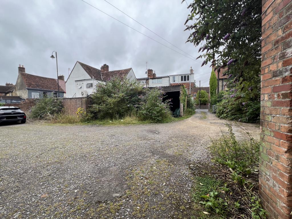 Lot: 100 - FORMER TRANSPORT YARD WITH POTENTIAL - General view of the two garages with overgrown bushes